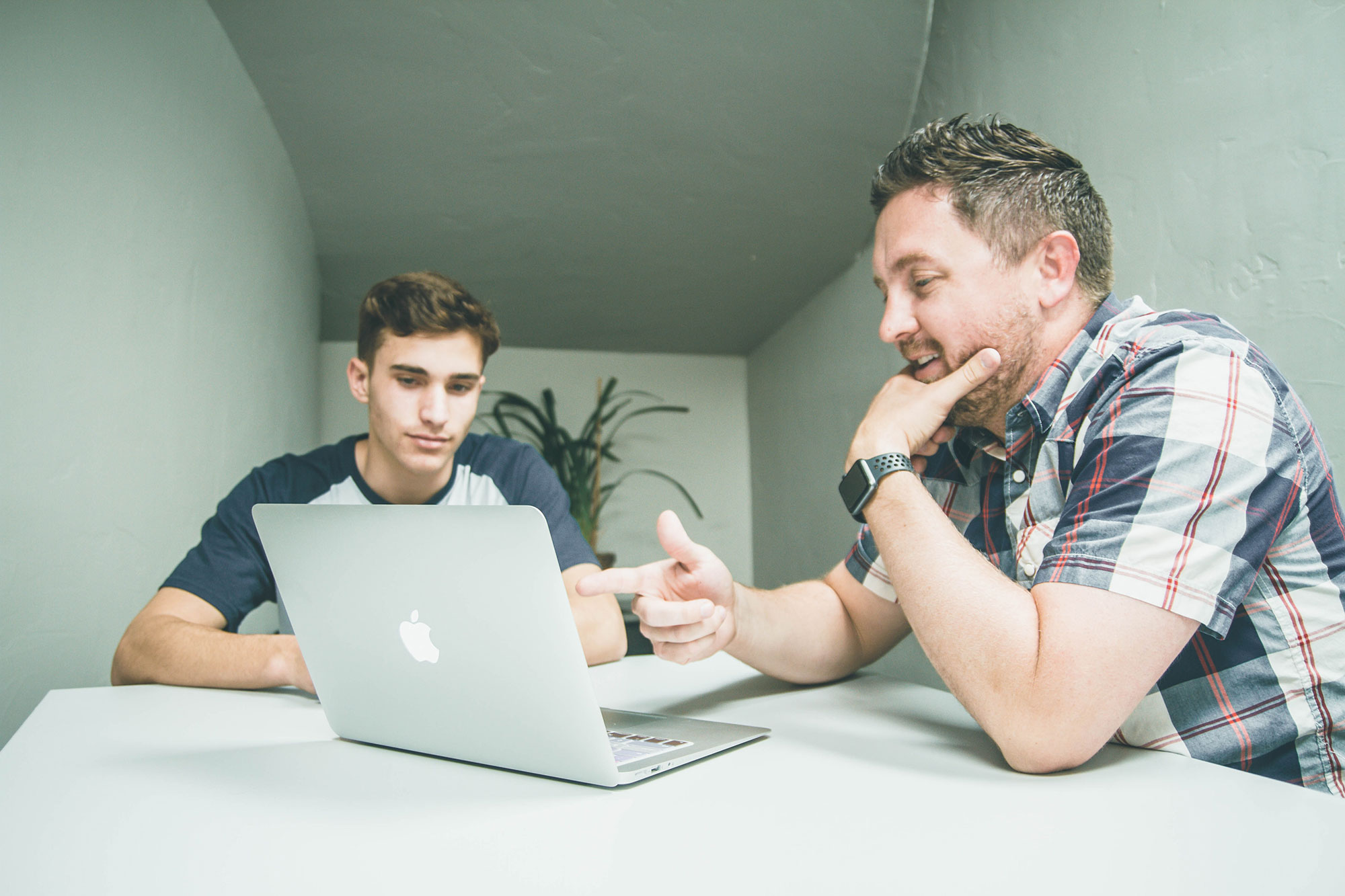 Men discussing page on a MacBook