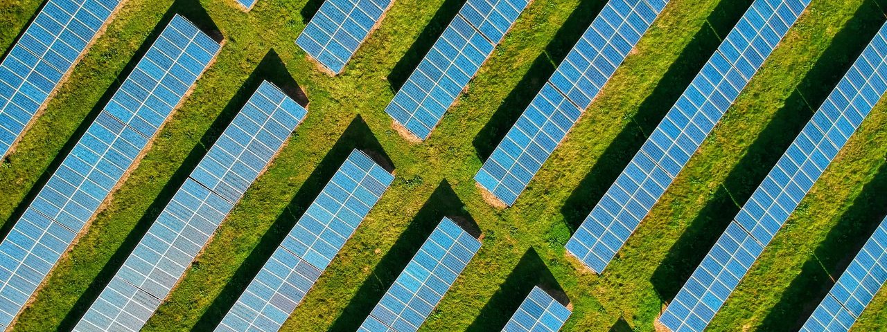 High-angle aerial shot of solar panels in a lush green field, located in Rockbeare, UK.