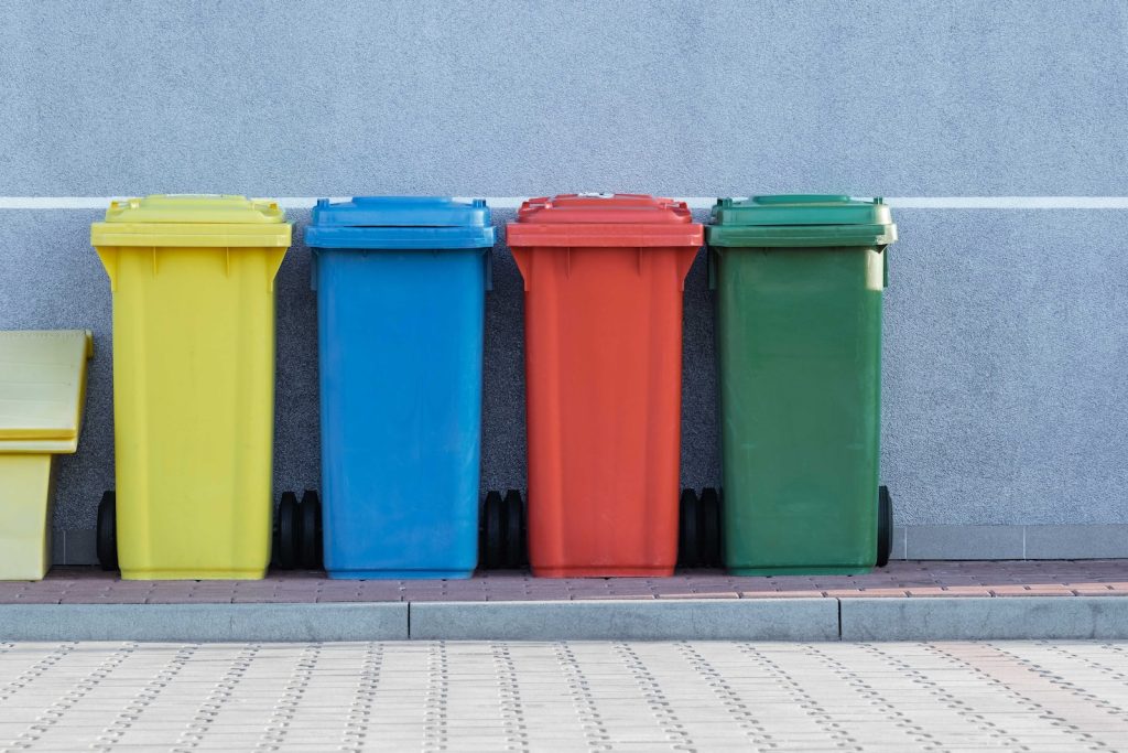 four assorted-color trash bins beside gray wall. sustainable renovation strategies