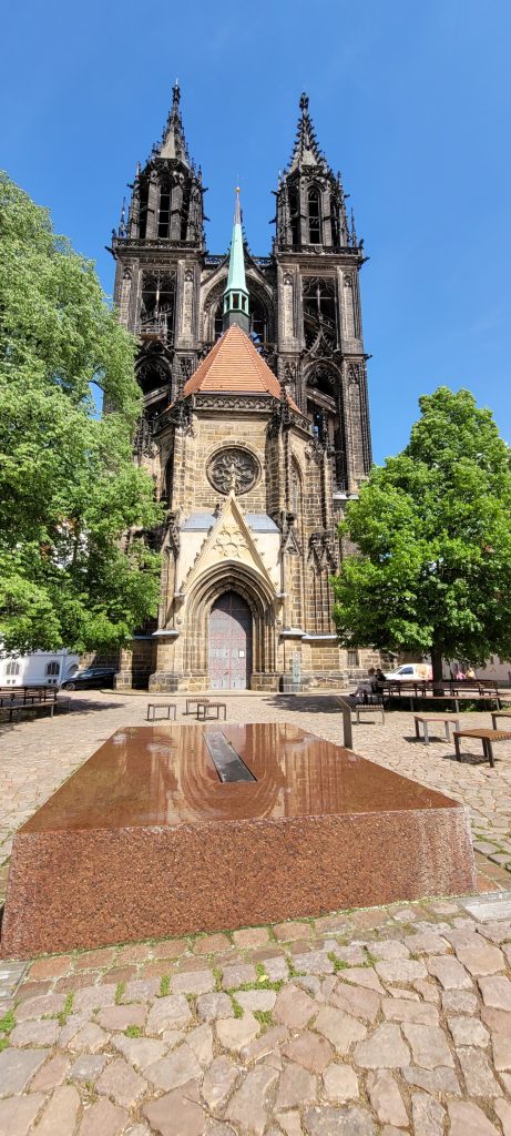 Blick auf Dom in Meißen, davor ein rechteckiger Stein aus dem Wasser läuft (Wasserspiel)