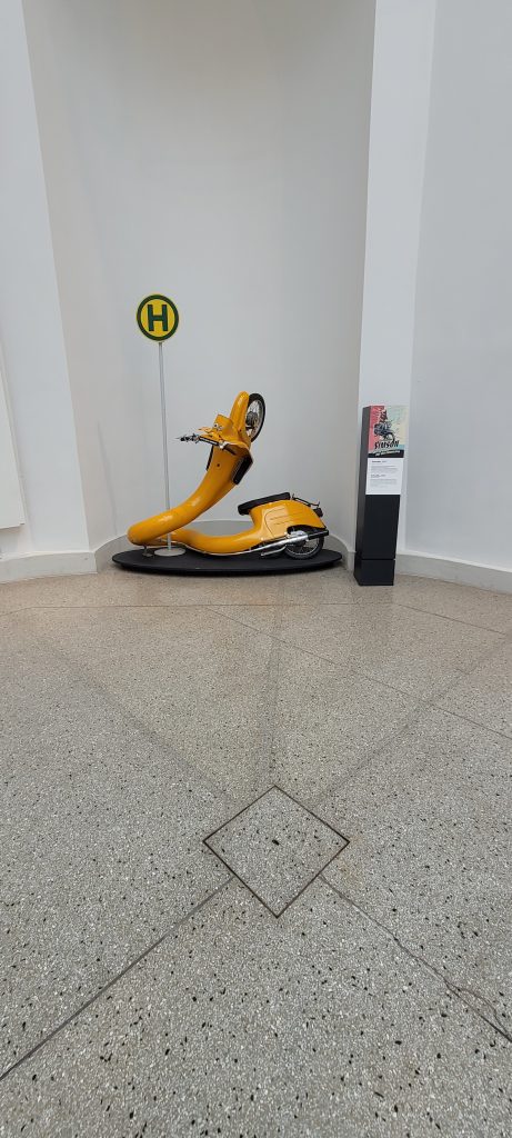 Ausstellungsstück im Verkehrskundemuseum Dresden, langgezogene gelbe Schwalbe an einem Haltestellenschild