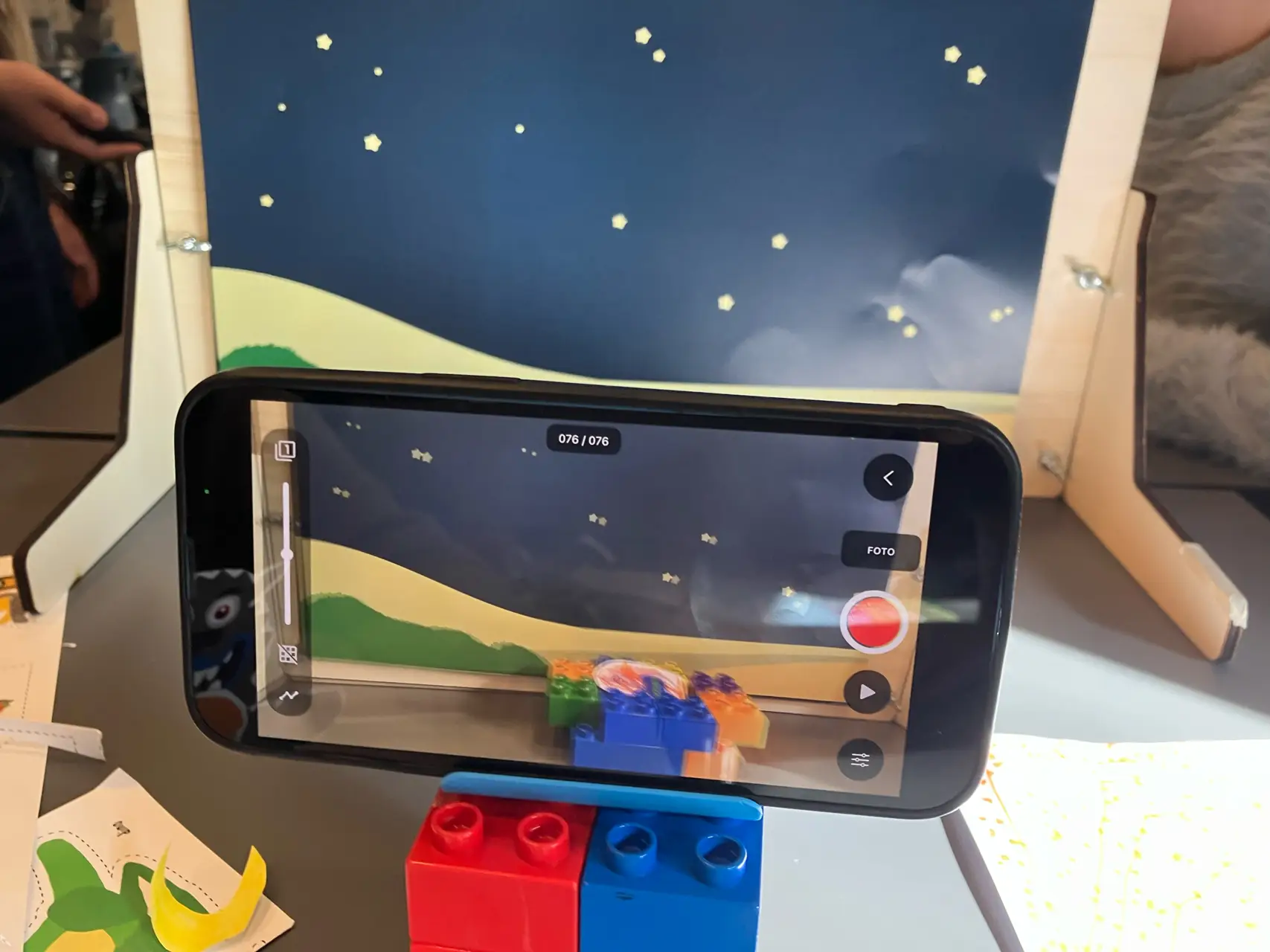 Tablet optager en stopmotionscene med farverige klodser foran stjernehimmel.