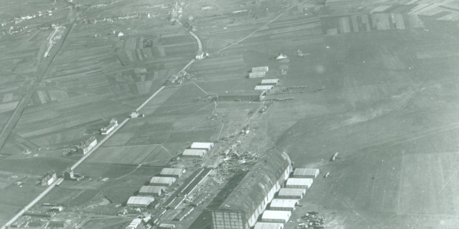 Luchtfoto van Haren-Evere, op 18 maart 1919 genomen door het duo piloot luitenant Jean Van Cotthem en waarnemer luitenant Jean Stampe. Links de Haachtsesteenweg. Merk de zeppelinloods en de houten vliegtuigloods. Overal liggen resten van Duitse militaire vliegtuigen. Dit is ongeveer wat de piloten en reizigers van de eerste burgervluchten naar Brussel moeten gezien hebben tijdens hun landing op Haren-Evere. (Archief Frans Van Humbeek)