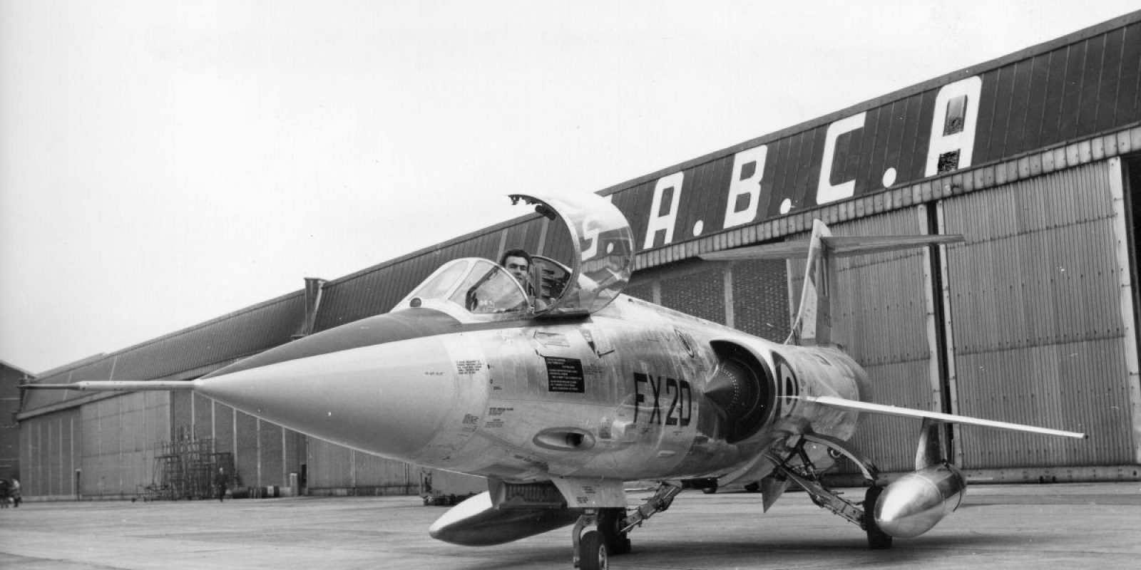 Le 30 octobre 1963, le FX-20 flambant neuf fait l’objet d’une séance photo avec le légendaire pilote Bernard Neefs. L’homme au « casque d ‘argent » est un pilote d’exception, très connu et populaire. Il a été « prêté » par son employeur Fairey à la SABCA pour la durée du programme F-104G. Il décèdera à 35 ans lors d’un accident d’avion à Gênes en Italie le 7 novembre 1965.