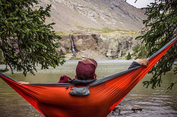 man hammock camping near river