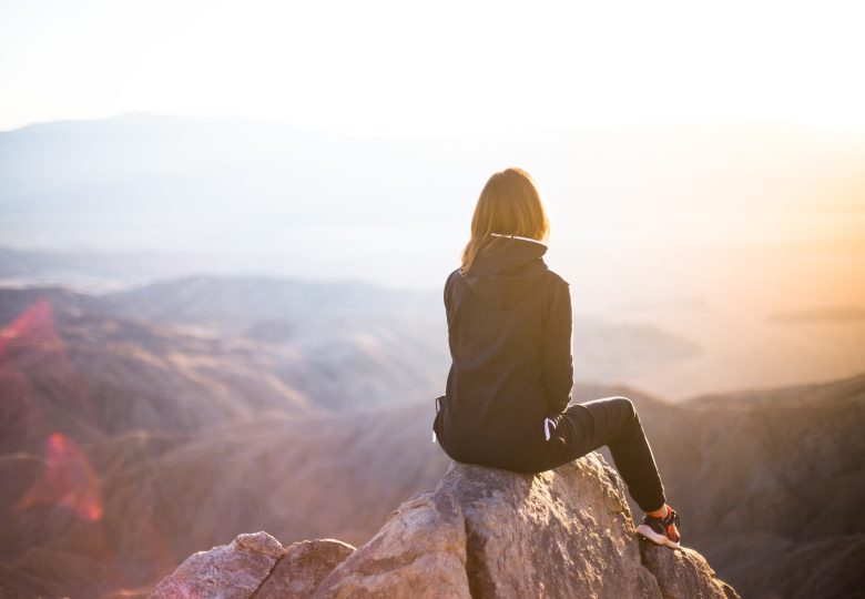 Kvinna på en klippa tittandes ut mot horisonten mot berg