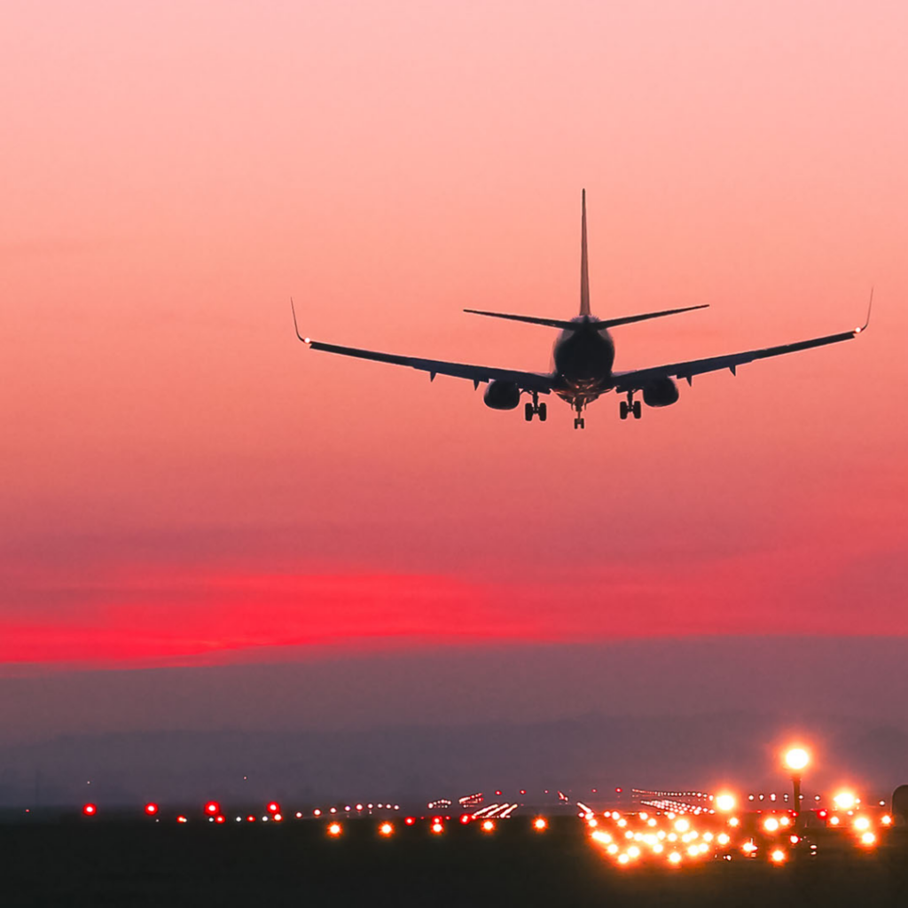 landingsstrip met landend vliegtuig, mooie rode zonsondergang op de achtergrond