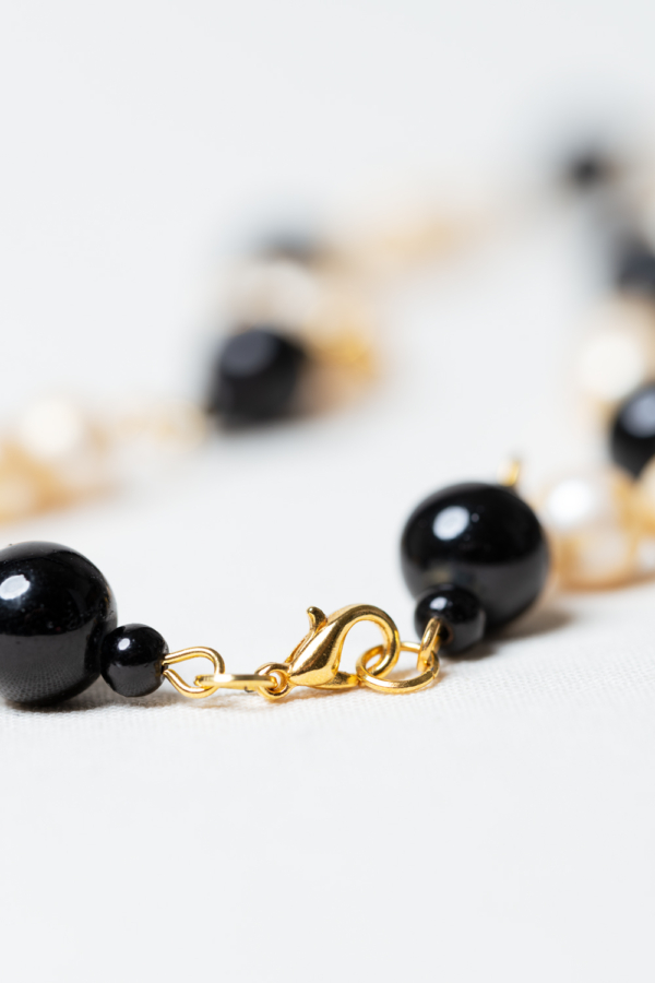 Golden necklace with vintage pearls and black glass beads closure