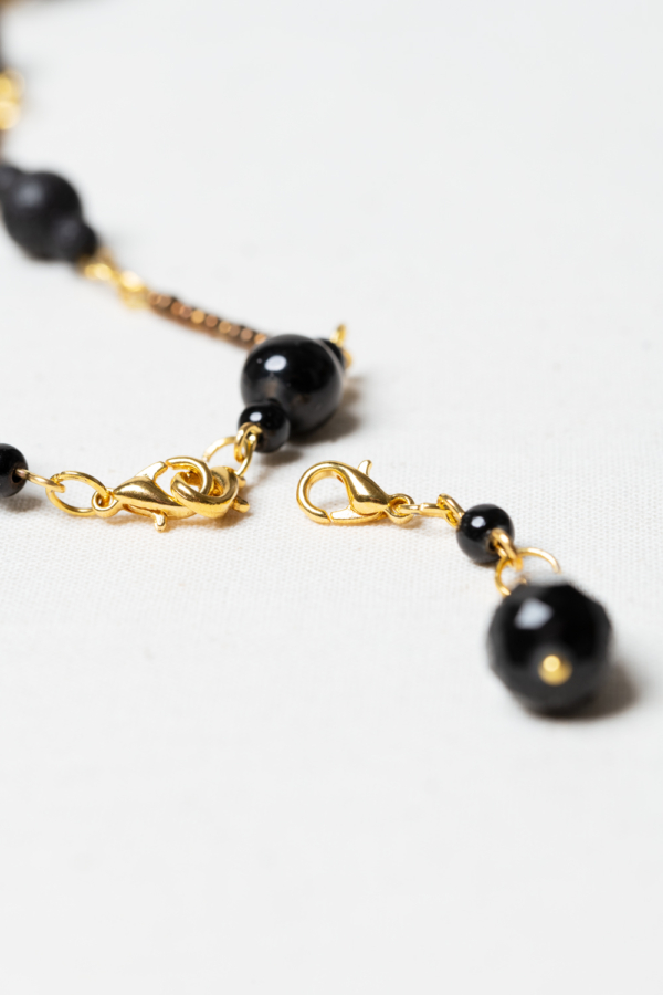 Long golden necklace with black beads and pendant