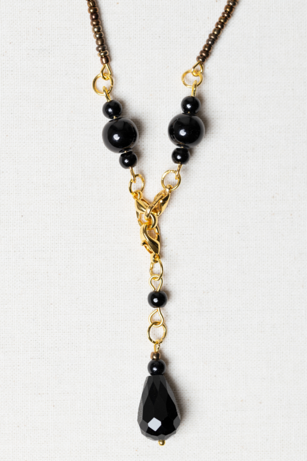 Long golden necklace with black beads and pendant