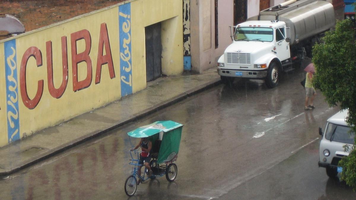Ein Bici-Taxi fährt bei strömenden Regen durch Havanna
