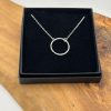 this exquisite piece of jewelry is beautifully presented in a sleek black box on a rustic wooden surface with prominent grain patterns.