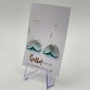 Discover a stunning pair of earrings featuring elegant silver hooks and exquisite blue, petal-shaped pendants, perfectly displayed on a white card. The card proudly showcases the Spotted Petal logo and is beautifully supported by a small, clear stand. Ideal for adding a touch of elegance to your jewelry collection.