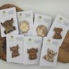 Wooden Pin Badges Featuring Engraved Animal Designs like Cows and Sheep, Presented on Cirrus Woodcraft Branded Cards and Displayed on a Rustic Wooden Surface.