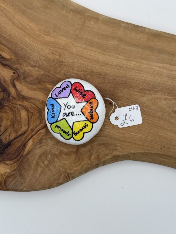 A beautifully crafted round stone, adorned with vibrant heart illustrations, features empowering words like Loved, Kind, Unique, Strong, Special, and Brave. At the center of this inspiring piece are the words You are... Perfect as a thoughtful gift or a meaningful decorative item, this painted stone rests elegantly on a wooden surface. Available now for just £6, its an affordable way to remind yourself or someone special of their incredible qualities.