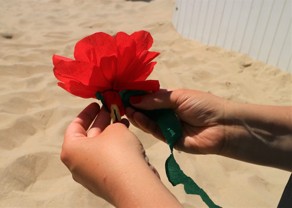 Twee handen tonen hoe je de groene steel bij strandbloemen maakt.