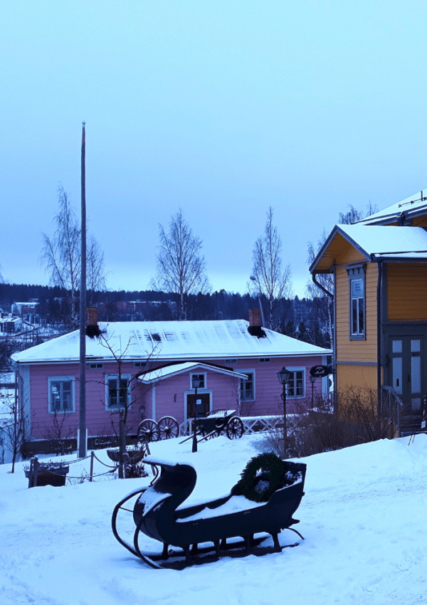 Kleurrijke huisjes in het centrum van de Finse stad Jyväskylä zijn bedekt met sneeuw. Op de voorgrond staat een arendslee.