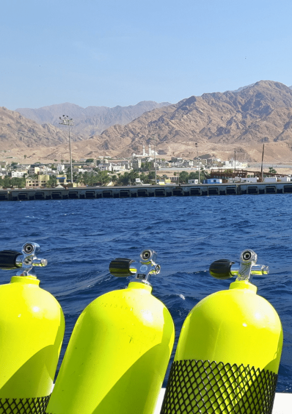 Felgele duikflessen staan naast elkaar op de rand van een duikboot in Aqaba, klaar voor de duikers die er op vakantie zijn.
