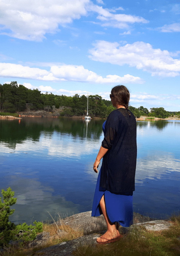 Een vrouw kijkt uit over het water in een natuurreservaat tijdens een rondreis door Zweden.