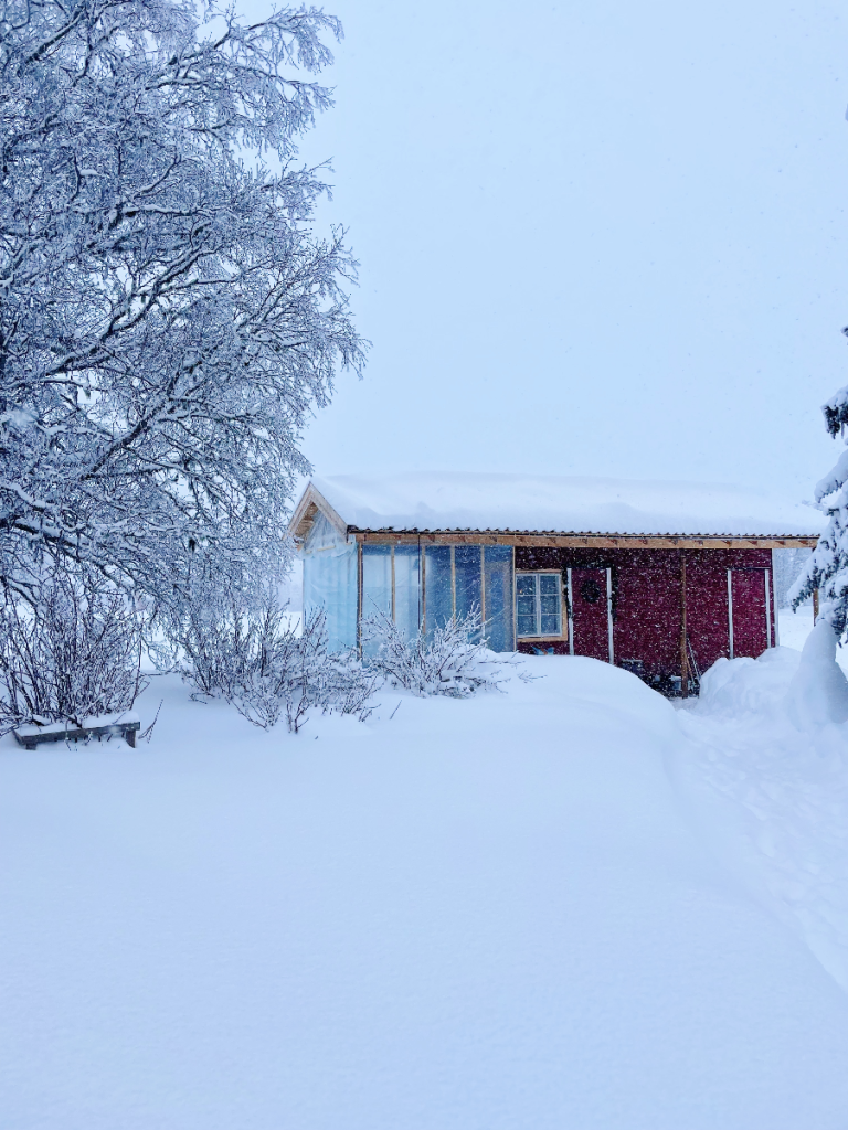 Cozy red backyard chicken coop in Norway, surrounded by snow.