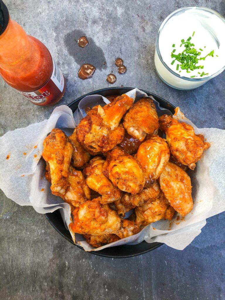 A bowl brimming with marinated chicken wings.