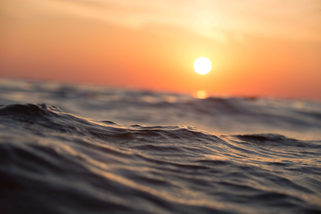 Image of a choppy sea with an orange sunseat in the background