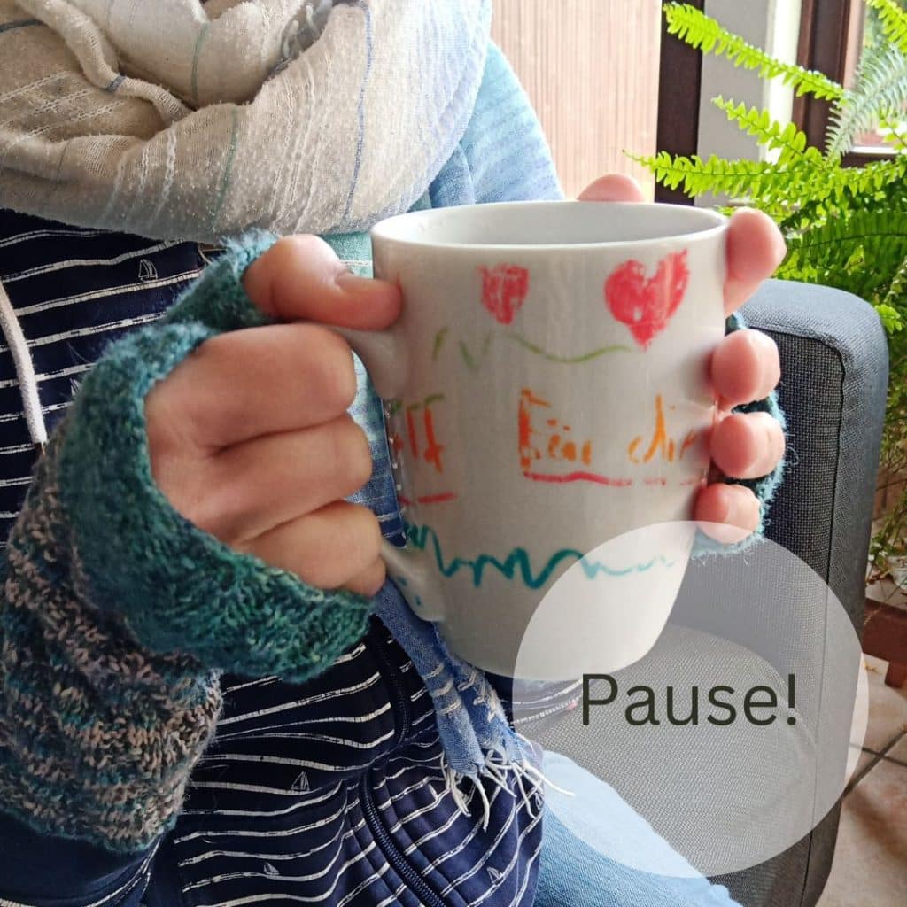 Suf dem Bild sind Hände zu sehen, die eine Tasse halten. Und das Wort Pause!