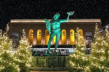 En Poseidonstaty i brons står omgiven av upplysta julgranar framför en upplyst byggnad på natten, med snöfall – vilket skapar en festlig scen i hjärtat av STÄDFIRMA HEDEN. En Poseidonstaty i brons står omgiven av upplysta julgranar framför en upplyst byggnad på natten, med snöfall – vilket skapar en festlig scen i hjärtat av STÄDFIRMA HEDEN.
