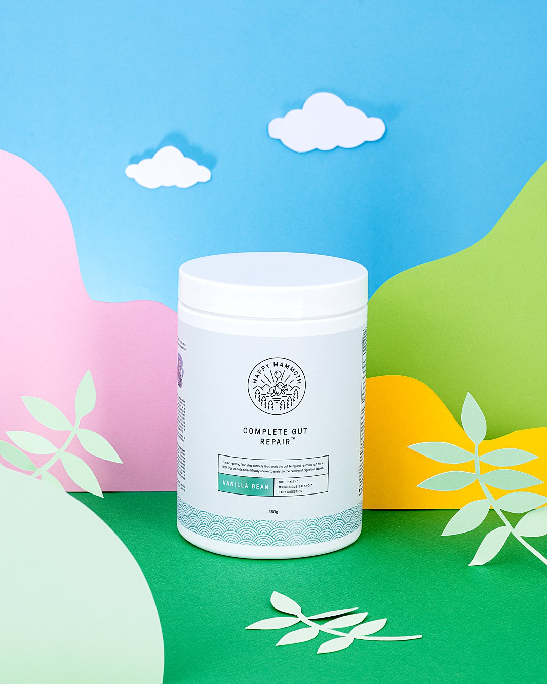 Colourful commercial photography with paper art for Happy Mammoth vitamin supplements. Styled health supplement product still life photography by HIYA MARIANNE photo production studio.