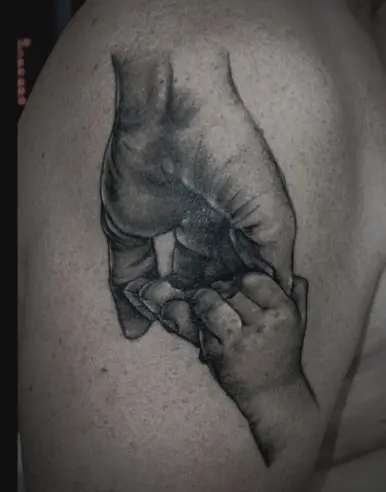 realistische tatoeage van hand die kinderhandje vast heeft