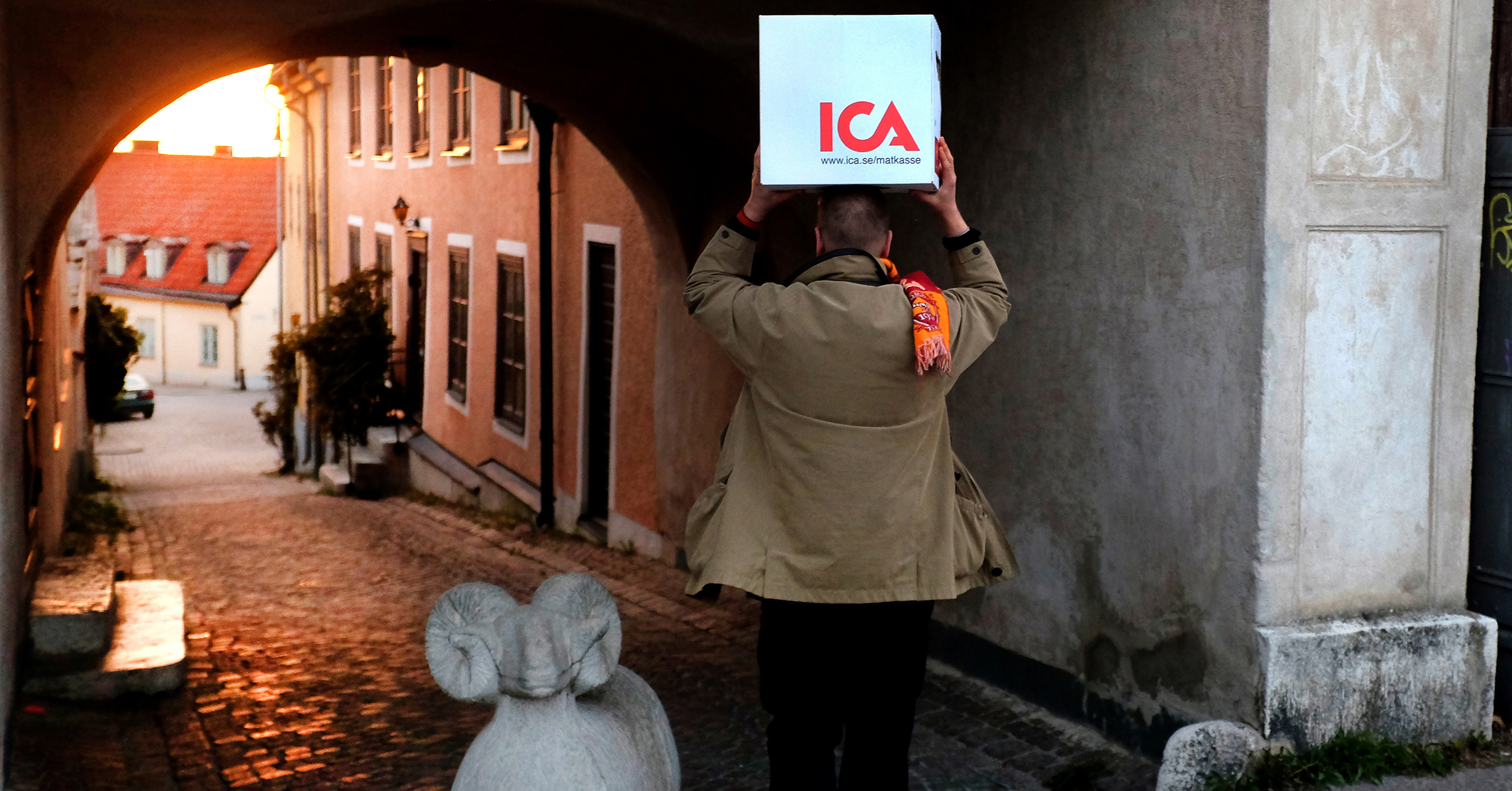 En man bär en låda med mat på huvudet, i Visby innerstad.