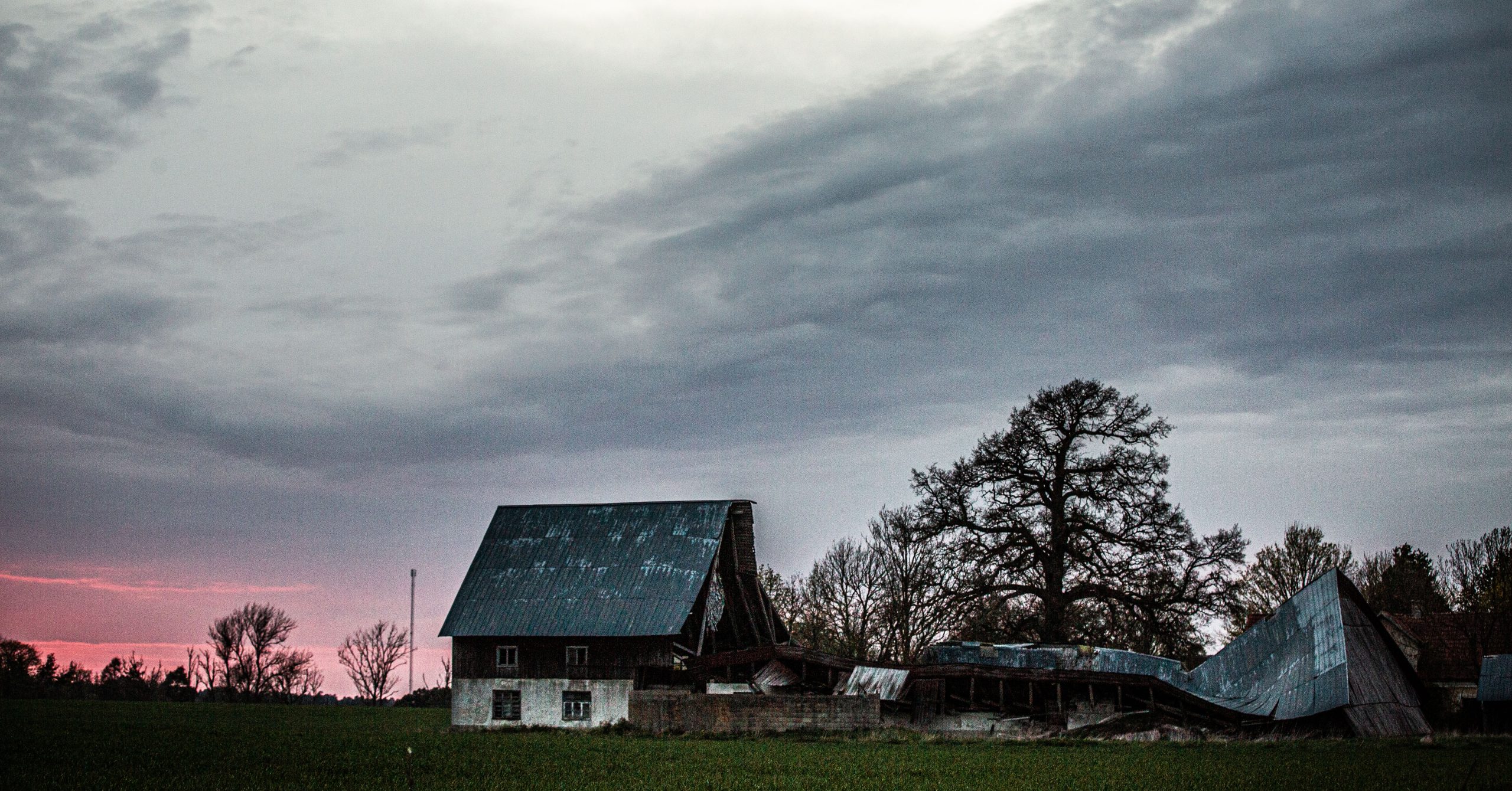 Ett ödsligt hus på landsbygden, framför en rosa himmel