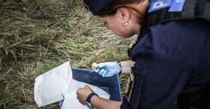 En polis undersöker en benbit ute i naturen