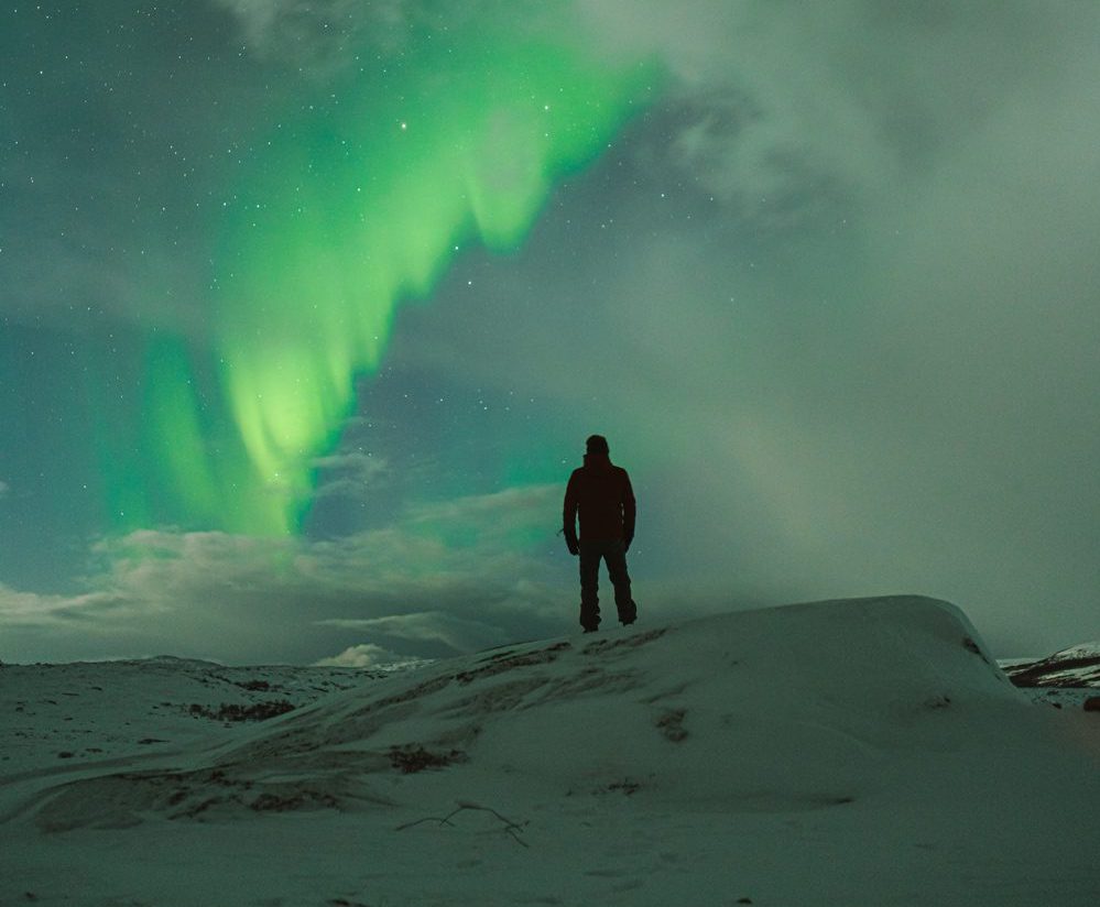 man står under ett norrsken i kiruna