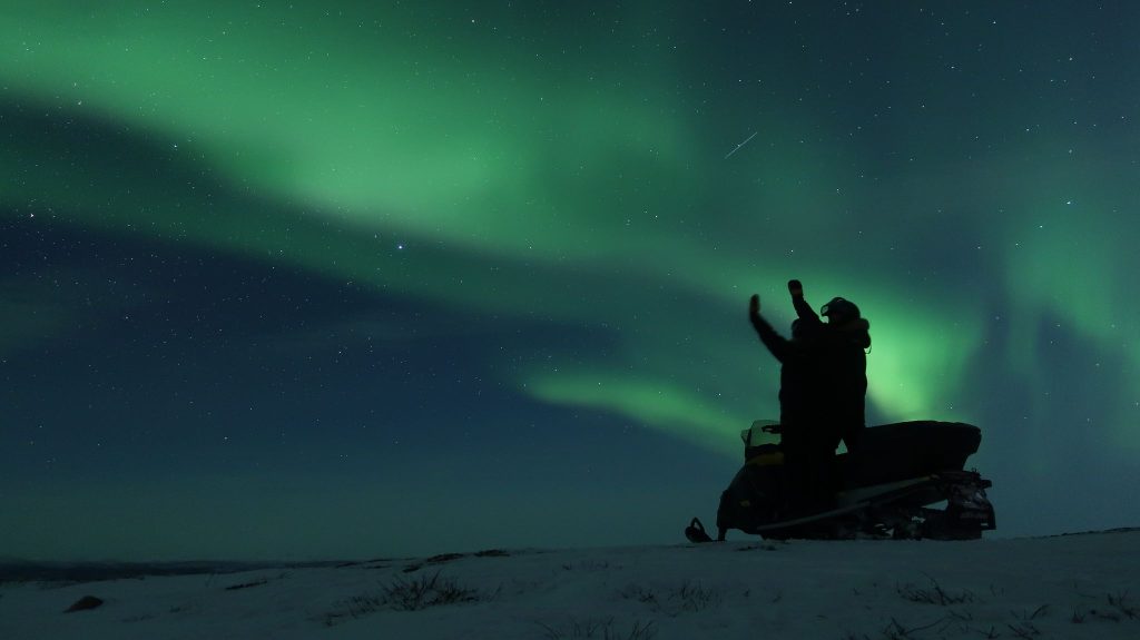 people on snowmobile watching northern lights kiruna Lapland