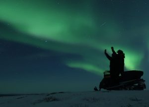 people on snowmobile watching northern lights kiruna Lapland