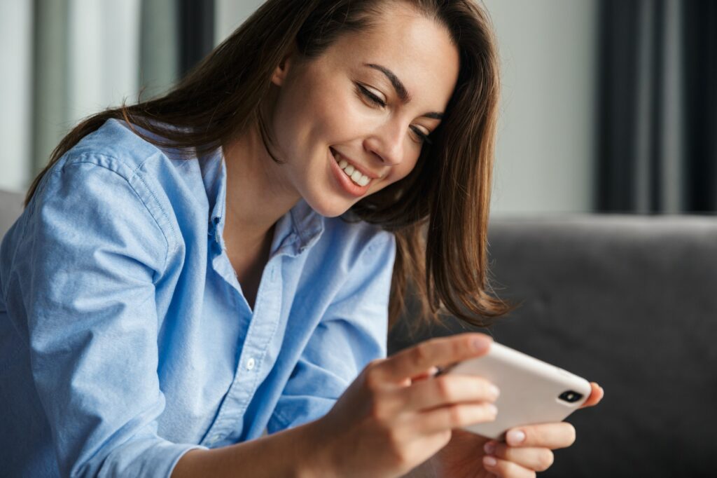 Image of woman playing video game on mobile phone while sitting