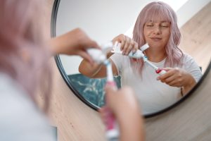 woman brushing teeth with electric toothbrush