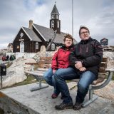 Two guests in Ilulissat on a bench in front of the church