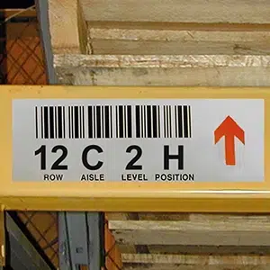 Abbildung einer Regal- oder Traversenkennzeichnung mit der barcodierten Aufschrift "Row 12" "Aisle C" "Level 2" "Position H" und einem Pfeil nach oben in Orange