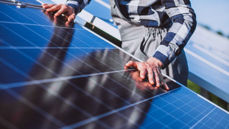 Man worker in the firld by the solar panels