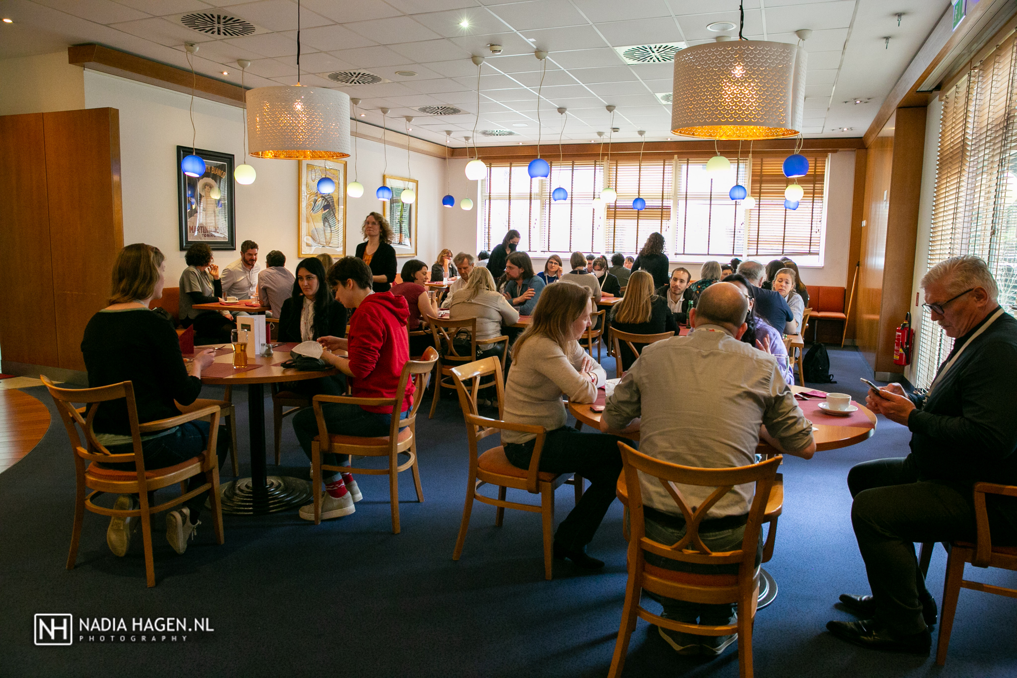 groups of four sit at tables in a hotel cafeteria for lunch