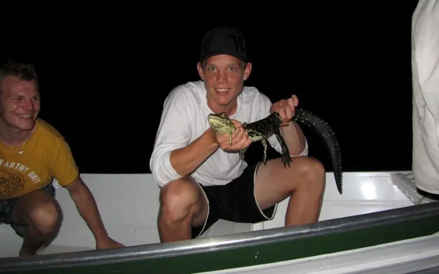 Guest holding a young caiman during a night safari with caimans near Tucan Amazon Lodge.