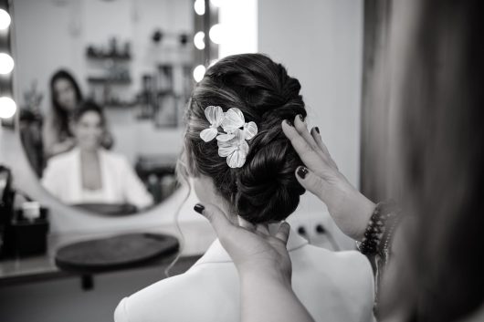 Stylist finishing a stylish hairstyle for a bride at the hair salon. Hairstyle concept.