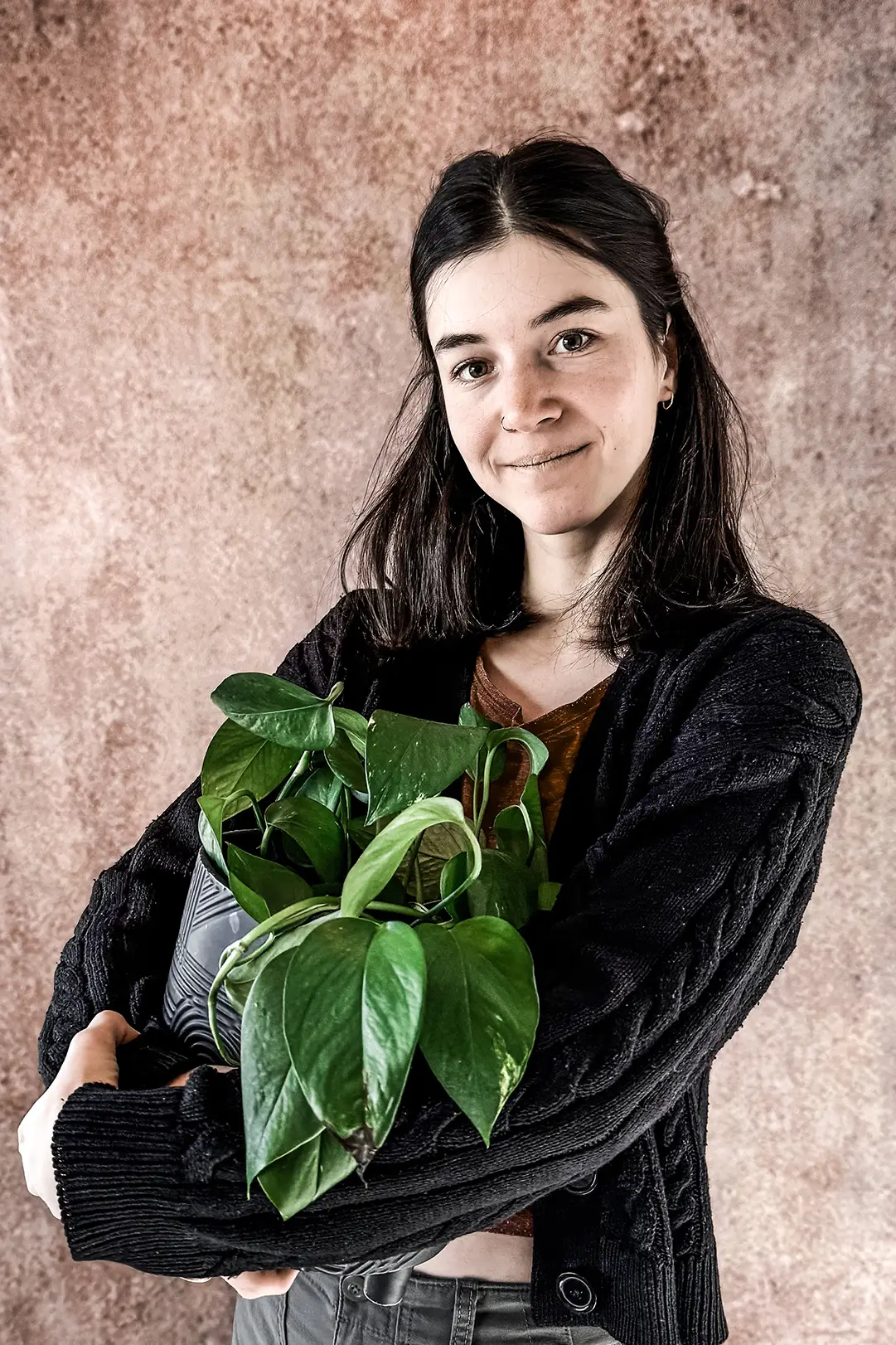 Tattoo-lærling regina hos inspirit tattoo i stavanger, smilende med en grønn plante i armene. Lærling hos anerkjent tatoveringsstudio.