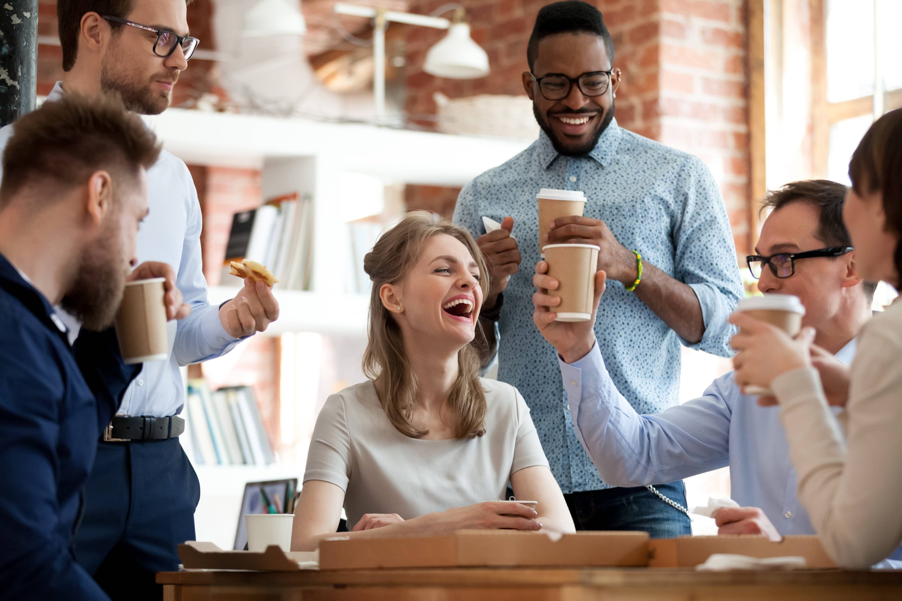 Une équipe de six personnes discutant et souriant en prenant un café