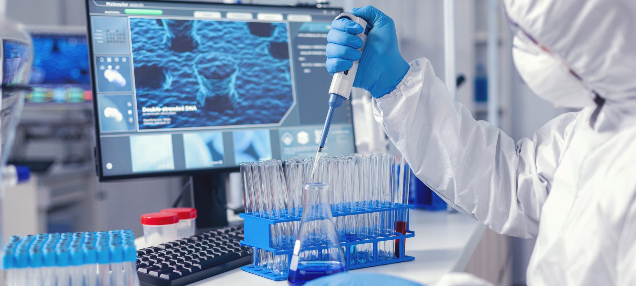 Virolog coducting experiment in the course of coronavirus pandemic with micropipette. Chemist in modern laboratory doing research using dispenser during global epidemic with covid-19.