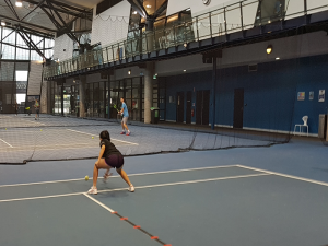 Foto de un tenista ciego jugando al tenis en una cancha de tenis cubierta.