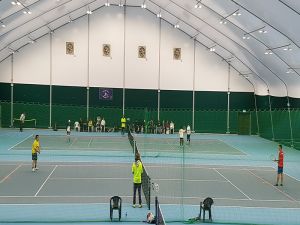 Foto de un tenista ciego jugando al tenis en una cancha de tenis cubierta.