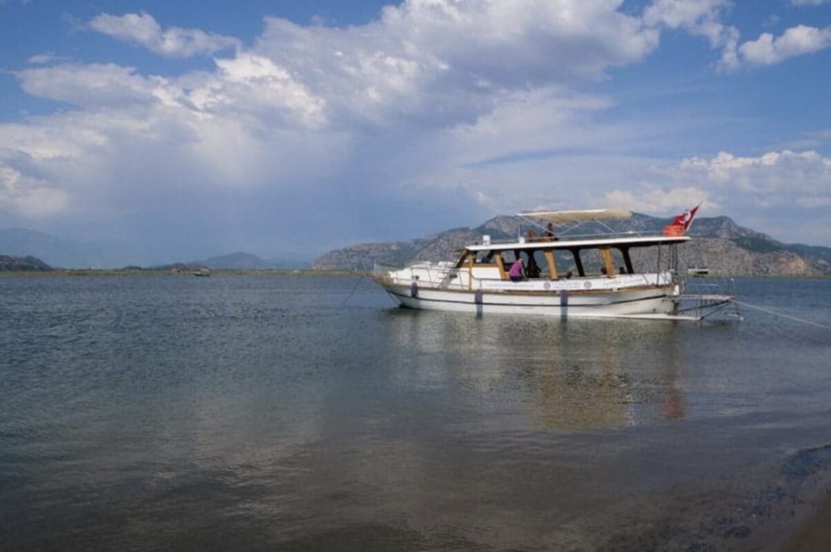 Boat anchored on a river with mountains in the background